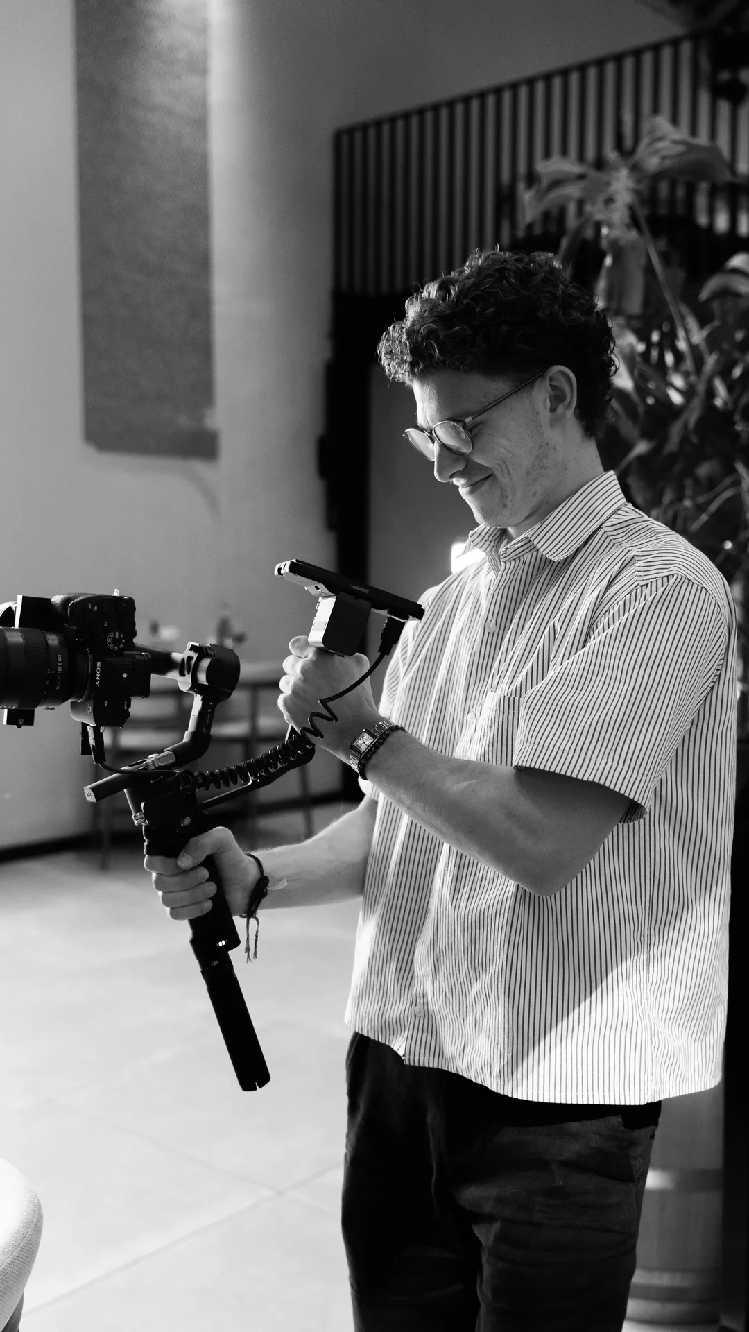 Maarten van Schijndel met zijn camera op een gimbal, kijkend naar het scherm. Zwart-wit.