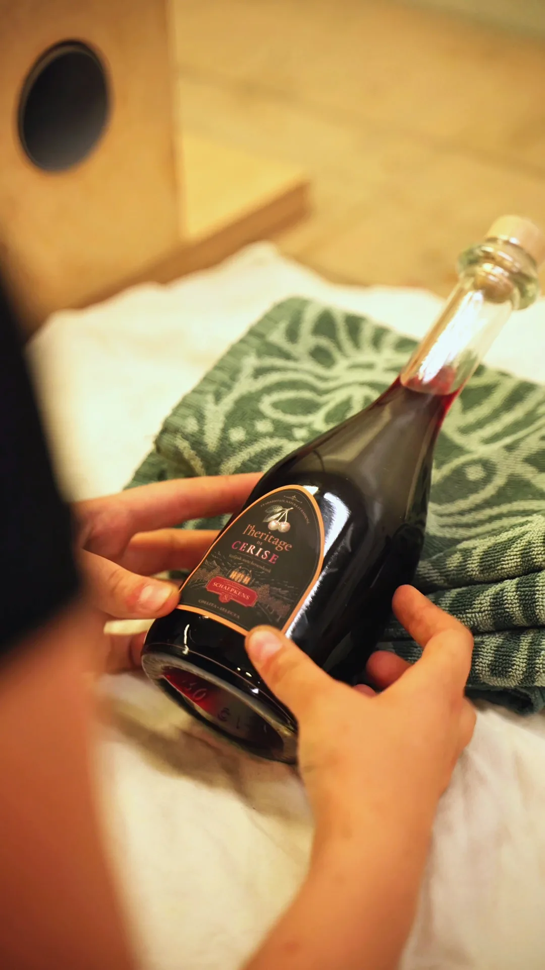 Handen met een fles kersenlikeur van Schaepkens.
